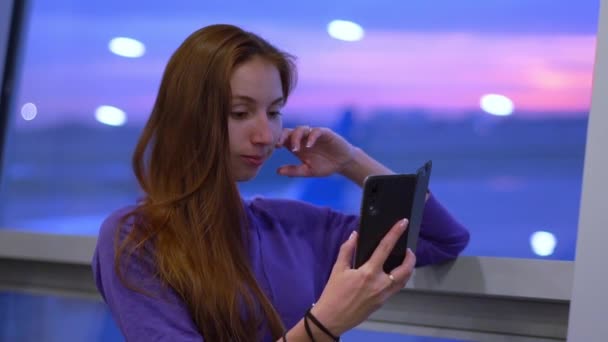 Morena chica lee e-book en el teléfono inteligente en el aeropuerto en cámara lenta — Vídeo de stock