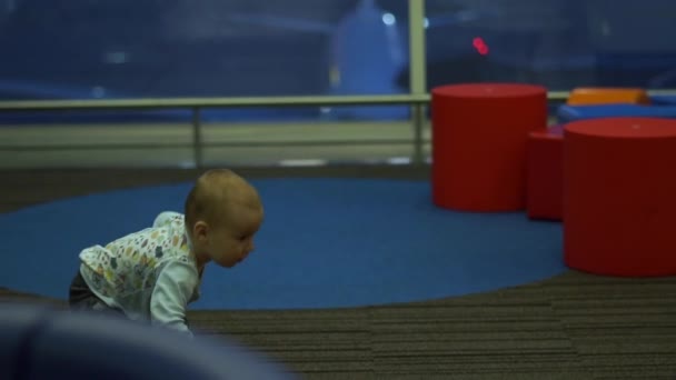 Un niño pequeño corre alegremente en el área de juegos para niños en el aeropuerto, en cámara lenta — Vídeo de stock