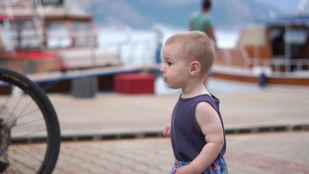 Anak kecil berambut pirang berjalan di sepanjang dermaga dalam gerakan lambat — Stok Video
