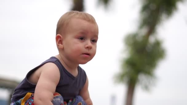 Pequeno menino bonito loiro olha em algum lugar com interesse, câmera lenta — Vídeo de Stock