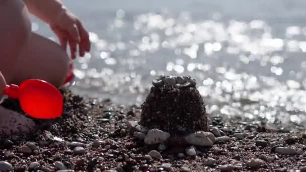 Een klein kind bouwt en vernietigt figuren op het strand in slow motion — Stockvideo