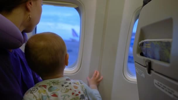 Flickan och hennes son tittar ut genom fönstret på planet i slow motion — Stockvideo