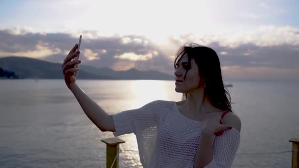 Jolie brune jeune femme fait des photos selfie contre la mer au lever du soleil au ralenti — Video