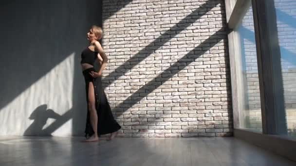 Blond meisje dansen overweegt in ruime studio met openslaande ramen in slo-mo — Stockvideo