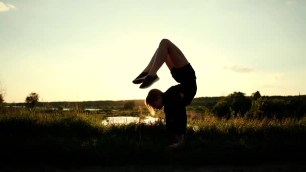 Slank meisje het doen van een handstand met benen gebogen terug en rechttrekken haar benen omhoog in slo-mo — Stockvideo