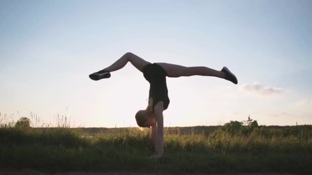 Arty ragazza che fa palo, anteriore diviso e un aquila-palo al tramonto in slo-mo — Video Stock