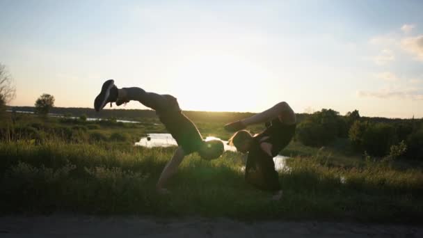 Brave man doet een krokodil handstand en zijn meisje doet een Pauw asana in slo-mo — Stockvideo