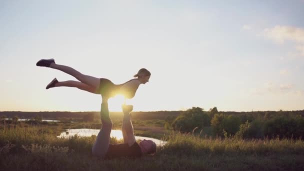 Hulk uomo si siede e tiene la sua ragazza sulle sue mani facendo una figura passero al tramonto in slo-mo — Video Stock