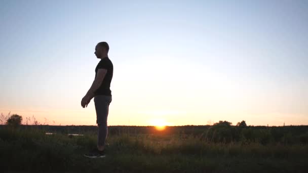 Homem salta um salto nas costas em um lago de cana em esplêndido pôr do sol em slo-mo — Vídeo de Stock