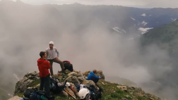 Bir grup turist dağlarda kayaüzerinde oturur. — Stok video