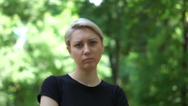 Mooie blonde vrouw vol verwachting in een groen park in slo-mo — Stockvideo