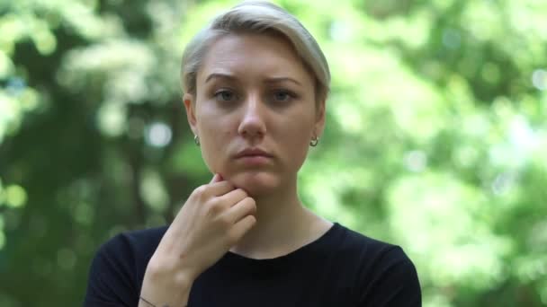 Atraktivní blonďatá žena, která se záhadně dívá do parku v poji — Stock video