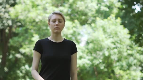 Pěkná blonďatá žena, která si dala ukazováček před rty v parku v poji — Stock video