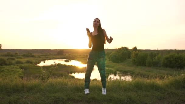 Felice giovane donna che balla con una bottiglia di vino al laghetto al tramonto a Slo-mo — Video Stock