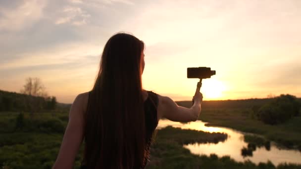 Jeune blogueuse fille fait de la vidéo avec son téléphone et sa carabine au coucher du soleil . — Video