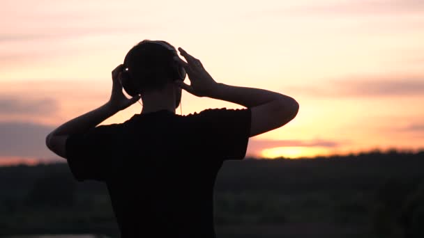 Χαρούμενος άνθρωπος στέκεται σε ακουστικά και κουνώντας το χέρι του στη μικρή λίμνη το ηλιοβασίλεμα σε αργή-mo — Αρχείο Βίντεο