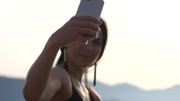 Молода дівчина робить селфі фото на фоні моря в повільному русі — стокове відео