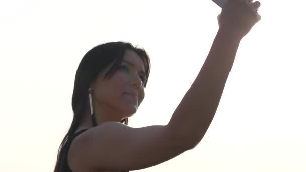 A pretty woman makes selfie photo on the background of the sea in slow motion — Stock Video