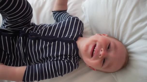 Счастливый ребенок лежит на кровати на белом простыне в замедленной съемке — стоковое видео
