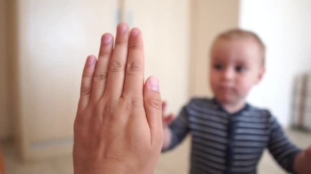 Un niño pequeño da cinco a una mano adulta en el interior en cámara lenta — Vídeos de Stock