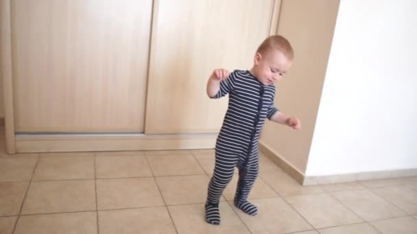 Menino bonito em um macacão listrado feliz pulando na sala em câmera lenta — Vídeo de Stock