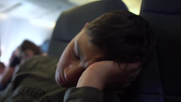 4k - Teen sleeping leaning his head on his arm in an airplane — Stock Video