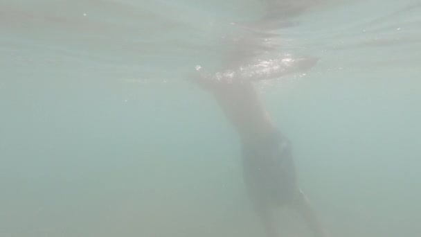 El niño hace una voltereta bajo el agua en el mar en cámara lenta — Vídeo de stock