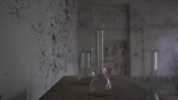 Okrągłe kolby medyczne i brudne rurki są na shabby stole w starej sali w SLO-mo — Wideo stockowe