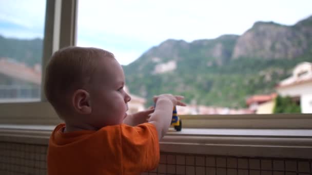 Un niño mira por la ventana y es jugado por el camión en cámara lenta — Vídeos de Stock