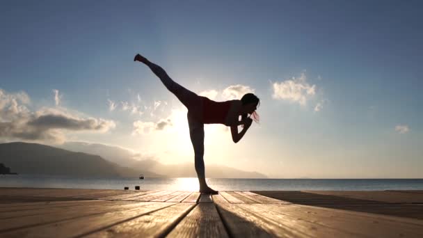 La mujer hace ejercicios de artes marciales, entrena en la playa junto al mar en cámara lenta — Vídeos de Stock