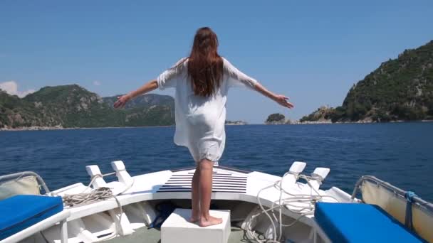 Dziewczyna stoi na dziobie łodzi z ramionami podniesioną na bok w zwolnionym tempie — Wideo stockowe