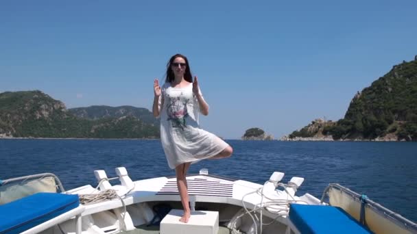 Ένα κορίτσι κάνει γιόγκα στην πλώρη ενός πλοίου, ενώ οδηγεί μπροστά από όμορφους λόφους — Αρχείο Βίντεο