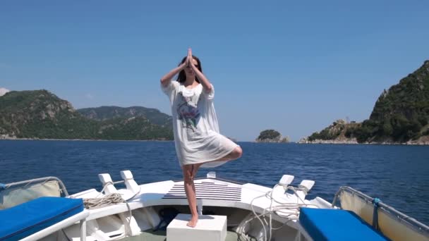 En flicka övar yoga på fören på en båt mot vackra kullar, slow motion — Stockvideo