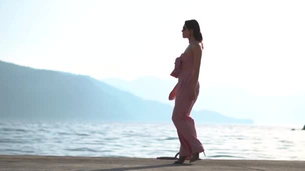 Стильная девушка-модель прогуливается по набережной в замедленной съемке на рассвете — стоковое видео