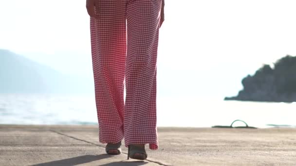 Egy nő magas sarkú sétál a tengerparton lassítva — Stock videók