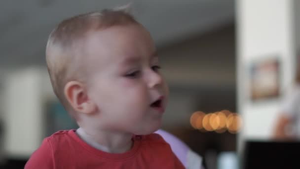 Menino pequeno engraçado vira a cabeça enquanto sentado em uma cadeira alta em câmera lenta — Vídeo de Stock