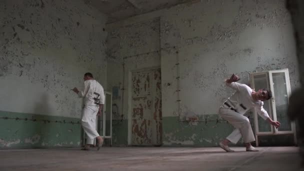 Two psycho men doing pitch tuck somersault in a shabby hall — Stock Video