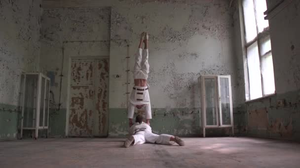 Deux kook men faisant un handstand dont un couché dans un hall collant — Video