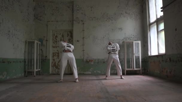 Two psycho men standing, bending back and turning in raggy room in slo-mo — Stock Video