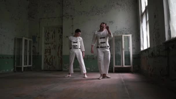 Two psycho men jumping, dancing and oing lunges in shaddy room in slo-mo — Stock Video