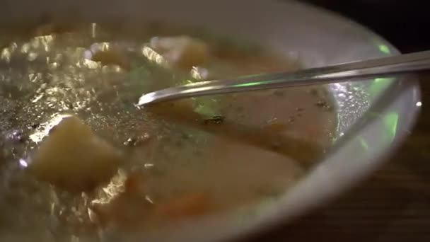 Πιάτο σούπας με ένα μεταλλικό κουτάλι σε μια σκοτεινή κουζίνα μέσα — Αρχείο Βίντεο