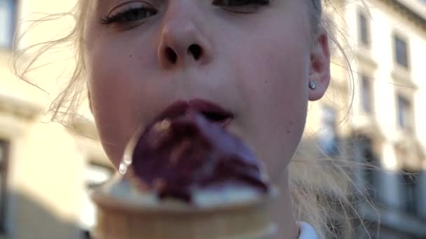 Vrolijk blond meisje staand en eten ijs in Krakau in de zomer in slo-mo — Stockvideo