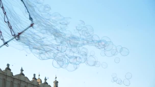 Много разноцветных мыльных пузырей летят над исторической площадью в Кракове летом — стоковое видео