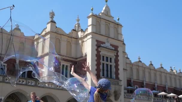 Multishaped soap bubbles are caught by happy children in Krakow square in summer — Stock Video
