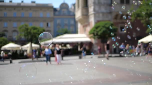 Lustiga tvål bubblor flyger lågt bland människor i Krakow Square på sommaren — Stockvideo