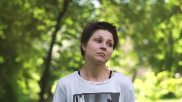 Verwirrte brünette Frau steht und zuckt mit den Schultern in einem Wald in Slo-mo — Stockvideo