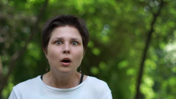 Scioccato bruna donna in piedi e guardando con la bocca aperta in un bosco in slo-mo — Video Stock