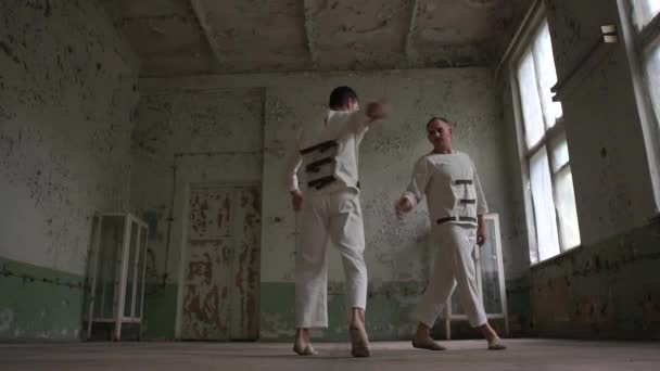 Two psycho men jumping and dancing breakdance together in a ragged room in slo-mo — Stock Video