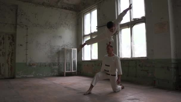 One nut man doing crocodile asana on one hand and the second helps him in slo-mo — Stock Video