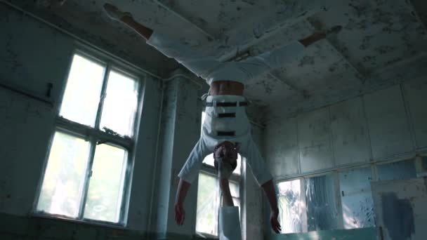 Två Loony män gör akrobatiska övningar och Huvudstående på benet i hallen i slo-mo — Stockvideo